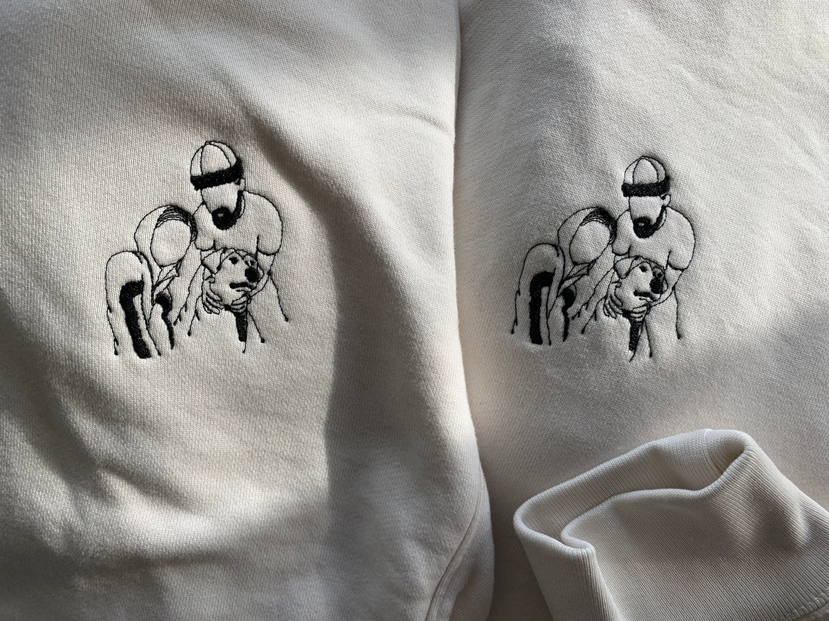 Close-up of a white sweatshirt showing the embroidered design on chest. Custom project from client's photo